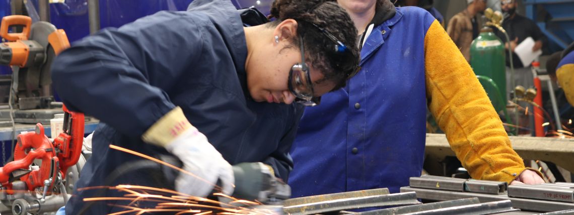 Opiskelija hitsaa ja toinen katsoo vierestä.